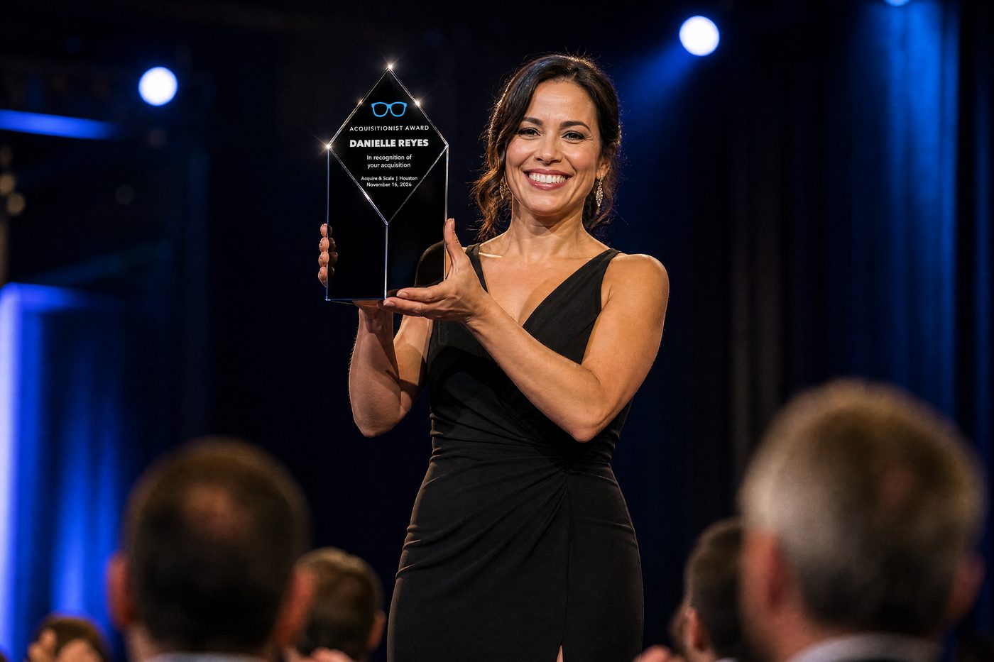 A winner holding up the black crystal Acquisitionist Award on stage
